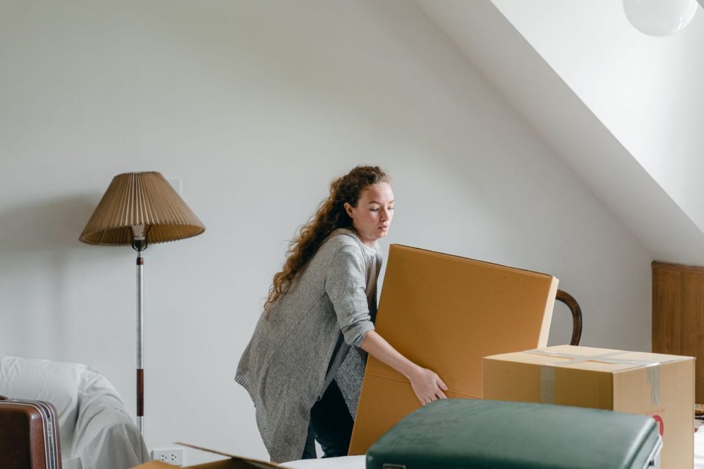 Zwei Personen tragen gemeinsam Umzugskartons aus einem Haus